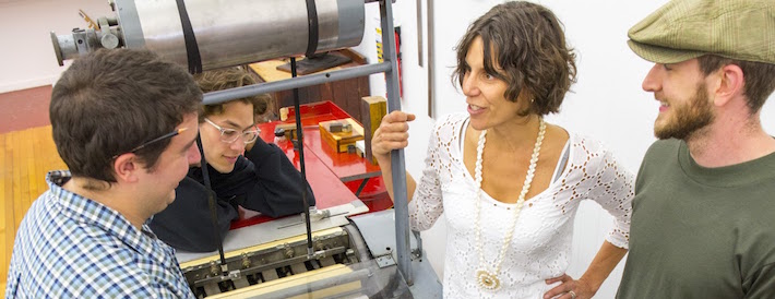 Professor talking to students next to a printing press